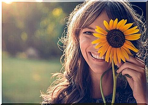 Smiling woman behind sunflower