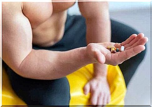 A muscular man holds some pills in his hand