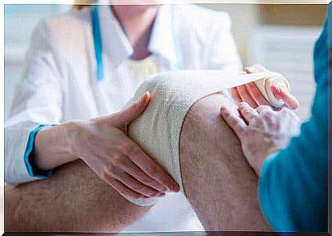 A doctor puts a bandage on a knee