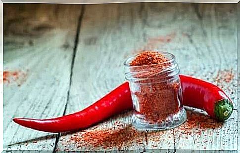 A jar of cayenne pepper next to a pepper