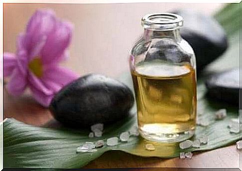 A bottle of essential oil with a black stone and a purple flower