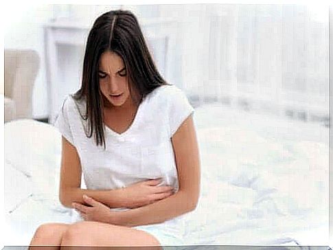 Woman sitting on bed with painful stomach