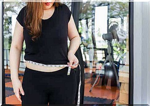 A woman holds a tape measure around her waist